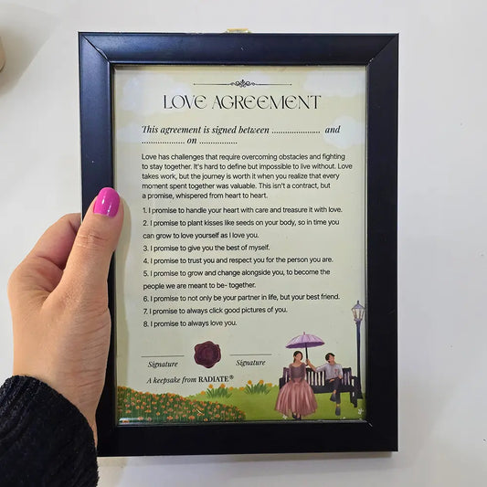 Hand holding a framed playful love agreement for couples.