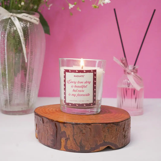 Love story scented candle by radiate on a wooden coaster against a pink background.