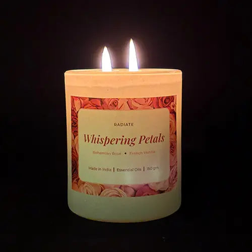 Radiate's Whispering Petals scented soy wax candle with aroma of Bohemian Rose and French Vanilla light up with two flames on a black background.