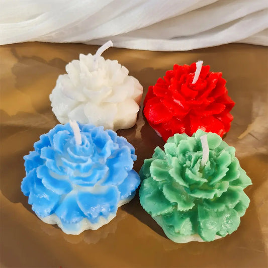 top view of four colorful peony flower-shaped pillar candles on a table.
