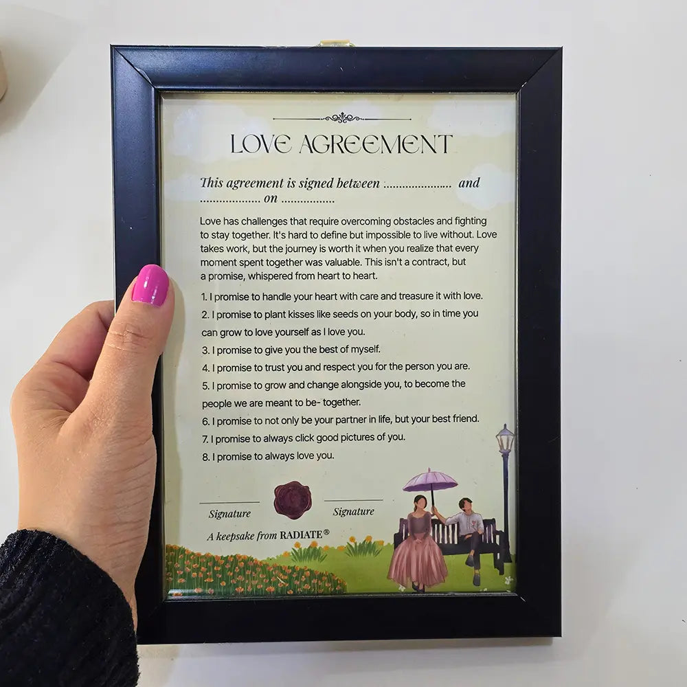 Hand holding a framed playful love agreement for couples.