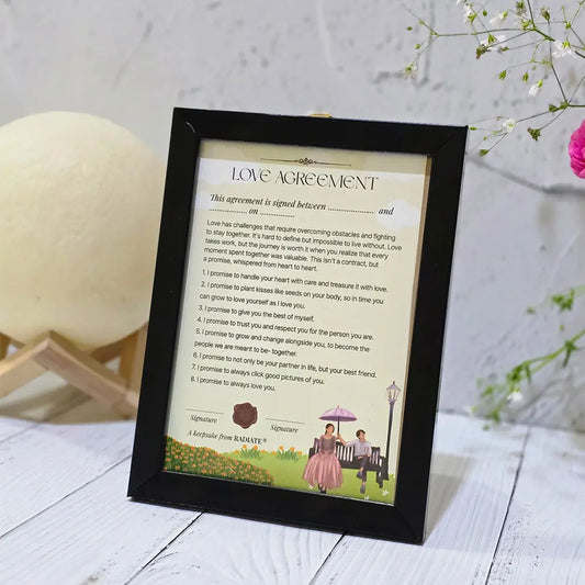Framed 'Love Agreement' by Radiate on a wooden surface with decorative elements.