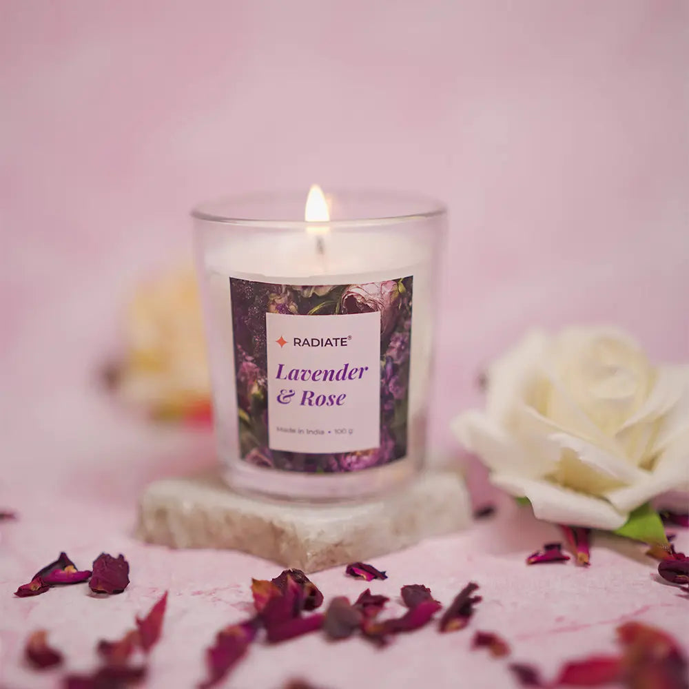Candle labeled 'Radiate Lavender & Rose' by Radiate with a white rose and dried flowers on a pink background