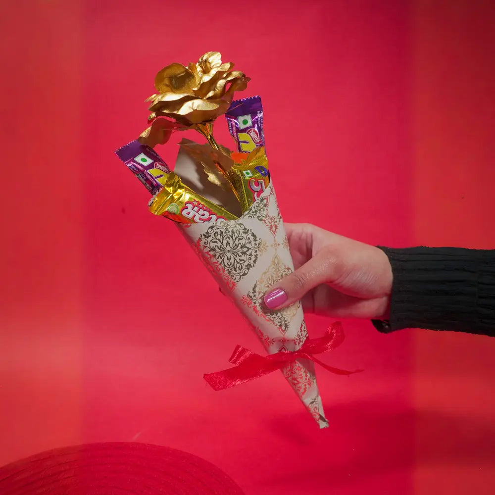 Hand holding a golden rose and chocolate bouquet 