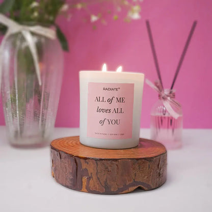 All of me musk scented candle with a romantic message on a wooden stand against a pink background