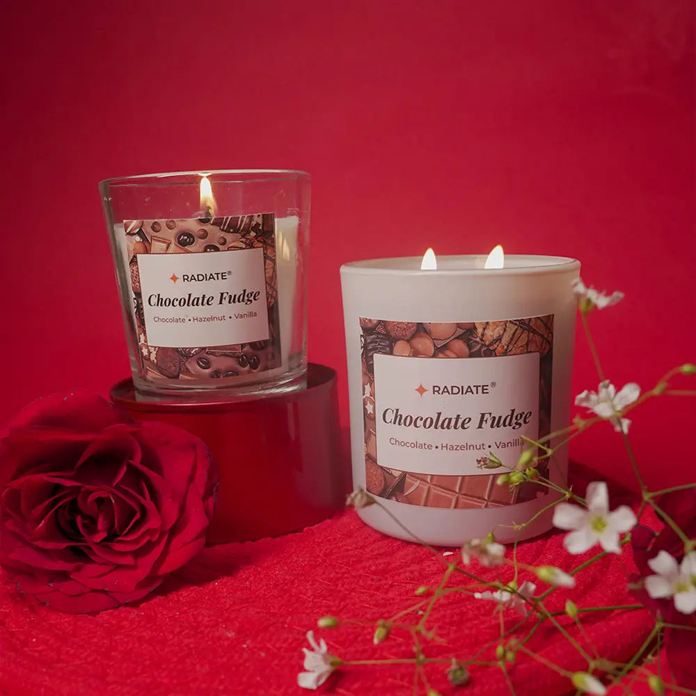 Two lit candles labeled 'Chocolate Fudge' on a red background with flowers and a rose.