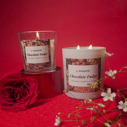 Two lit candles labeled 'Chocolate Fudge' on a red background with flowers and a rose.