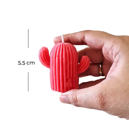 Hand holding a red cactus-shaped scented pillar candle with a measurement label on a white background
