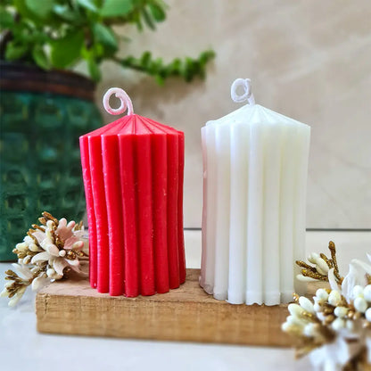 Red and white ribbed scented pillar candles on a wooden block with decorative elements.
