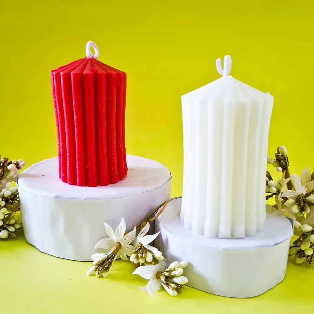 Two ribbed stripe scented pillar candles, one red and one white, on a yellow background with floral decorations.